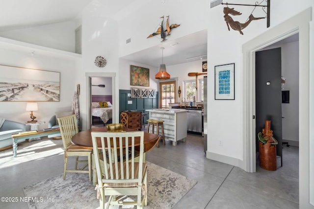 dining room with high vaulted ceiling and concrete floors