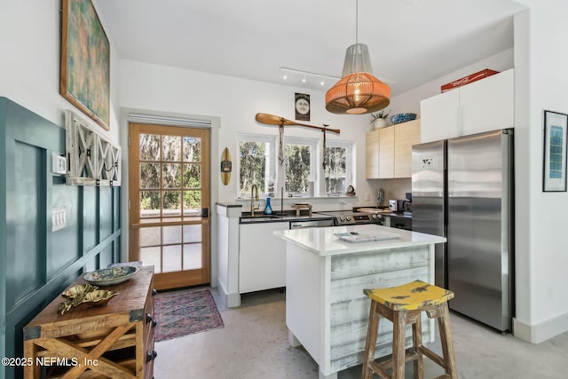 kitchen with white cabinets, pendant lighting, a center island, and stainless steel refrigerator