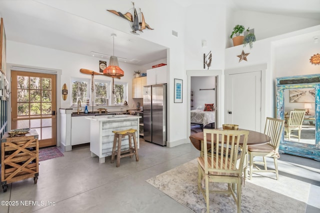 kitchen with white cabinetry, stainless steel fridge, a center island, and decorative light fixtures