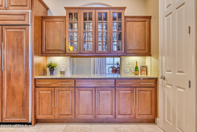 kitchen with light tile patterned floors, backsplash, and light stone counters