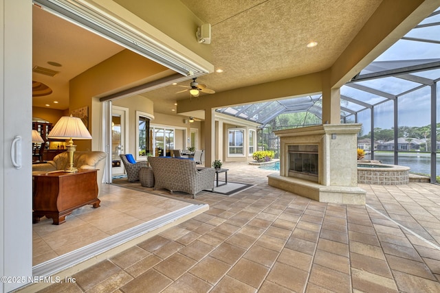 view of patio featuring a water view, an outdoor living space with a fireplace, and an in ground hot tub