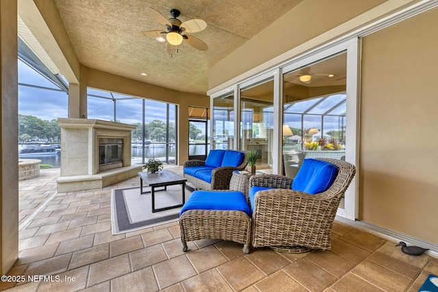 sunroom / solarium with ceiling fan and a water view