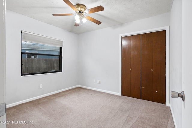 unfurnished bedroom with a textured ceiling, ceiling fan, a closet, and carpet