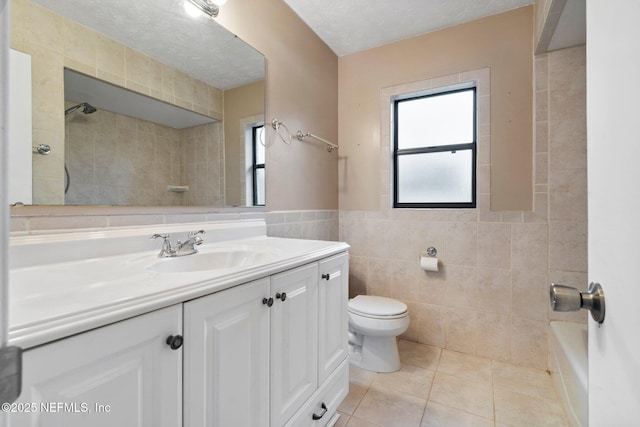 full bathroom with toilet, vanity, tile patterned floors, tile walls, and a textured ceiling