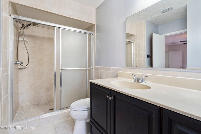 bathroom featuring walk in shower, vanity, tile patterned floors, and toilet