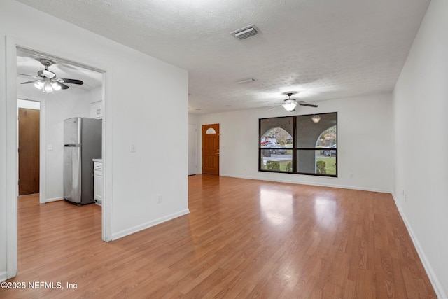 spare room featuring a textured ceiling and light hardwood / wood-style floors