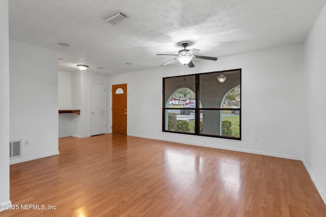 unfurnished room featuring a textured ceiling, ceiling fan, and light hardwood / wood-style flooring