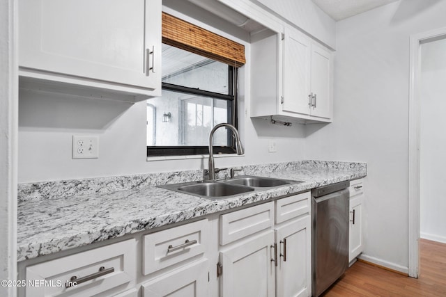 kitchen with white cabinets, stainless steel dishwasher, light hardwood / wood-style floors, and sink