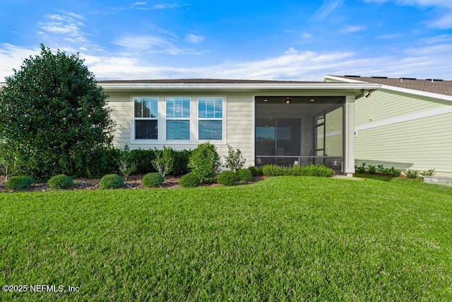 rear view of house with a sunroom and a yard