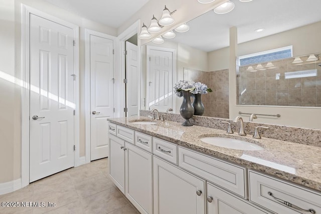 bathroom featuring tile patterned flooring, a tile shower, and vanity