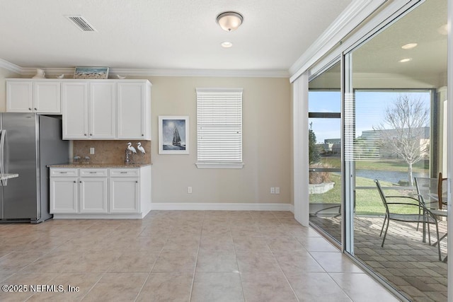 kitchen featuring light tile patterned flooring, white cabinetry, stainless steel refrigerator, and tasteful backsplash