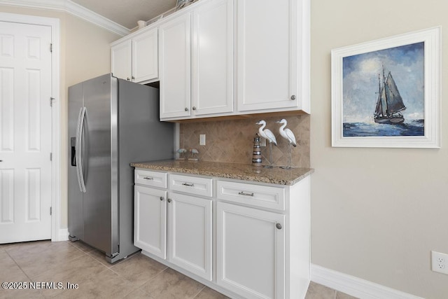 kitchen with light stone countertops, stainless steel fridge, backsplash, white cabinetry, and light tile patterned flooring