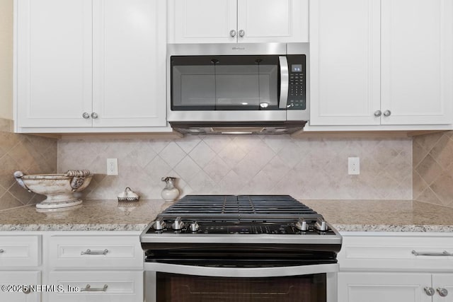 kitchen with decorative backsplash, white cabinets, light stone countertops, and appliances with stainless steel finishes