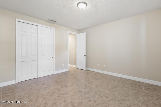 unfurnished bedroom featuring a textured ceiling and a closet