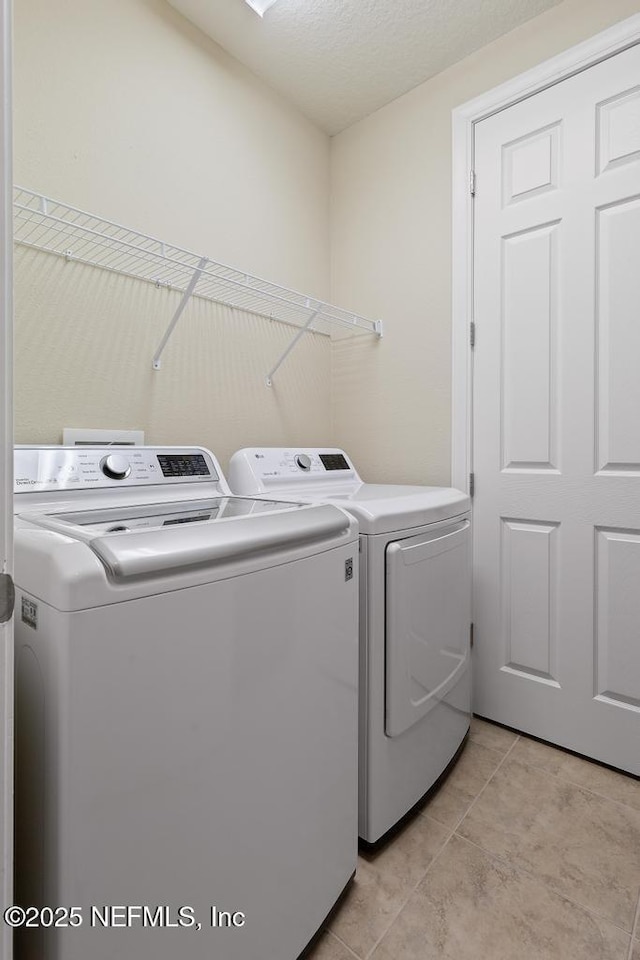 laundry area featuring washer and clothes dryer and light tile patterned floors