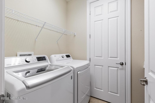 clothes washing area featuring washer and clothes dryer and light tile patterned flooring