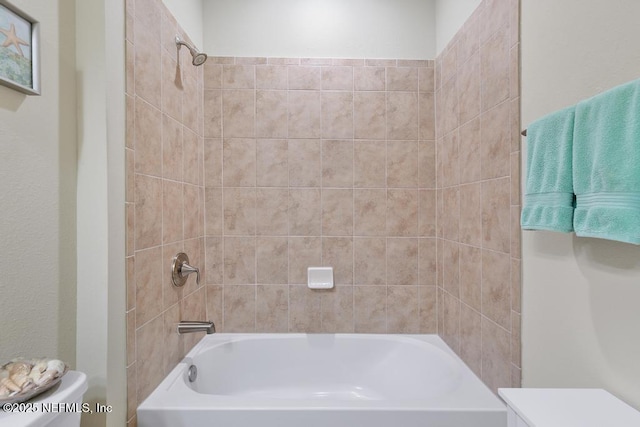 bathroom featuring toilet and tiled shower / bath