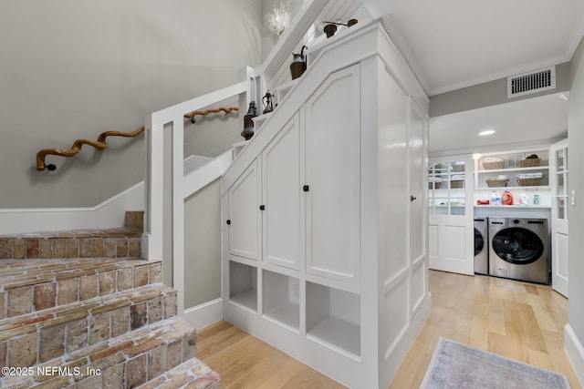 laundry area with washer and dryer, light hardwood / wood-style floors, built in shelves, and ornamental molding