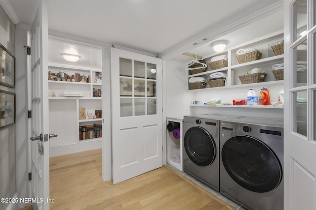 clothes washing area featuring separate washer and dryer, light hardwood / wood-style flooring, and ornamental molding