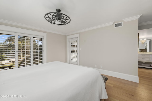 bedroom featuring light wood-type flooring, ornamental molding, an inviting chandelier, and ensuite bath