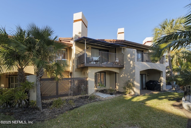 rear view of property with a balcony and a yard