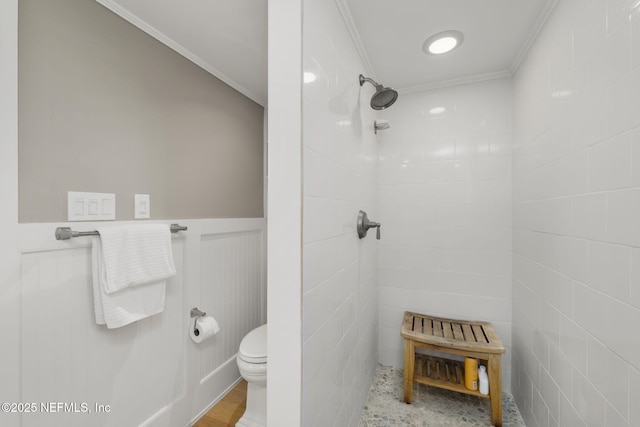 bathroom with a tile shower, toilet, and ornamental molding