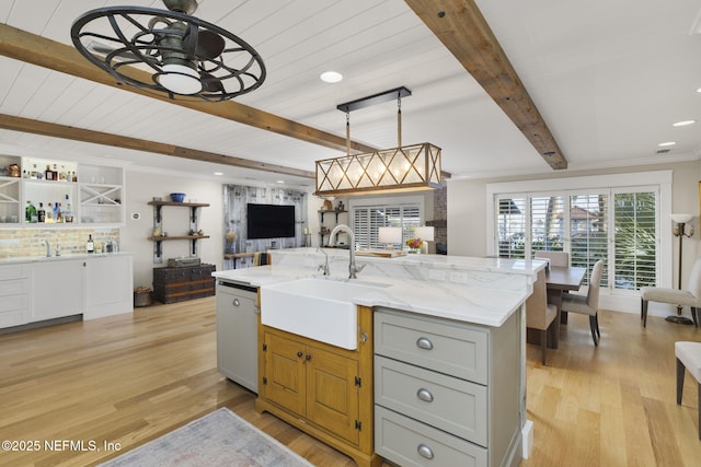 kitchen featuring pendant lighting, white dishwasher, sink, gray cabinets, and an island with sink