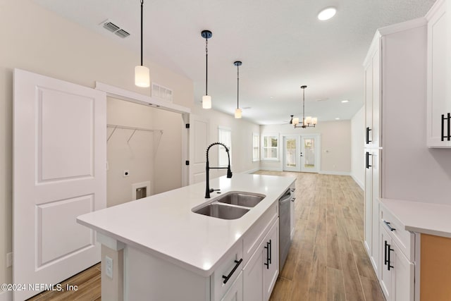 kitchen featuring decorative light fixtures, white cabinetry, a kitchen island with sink, and sink