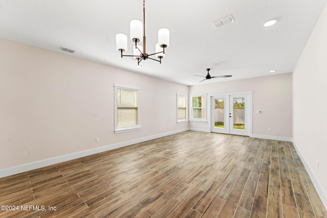 empty room featuring ceiling fan with notable chandelier and french doors