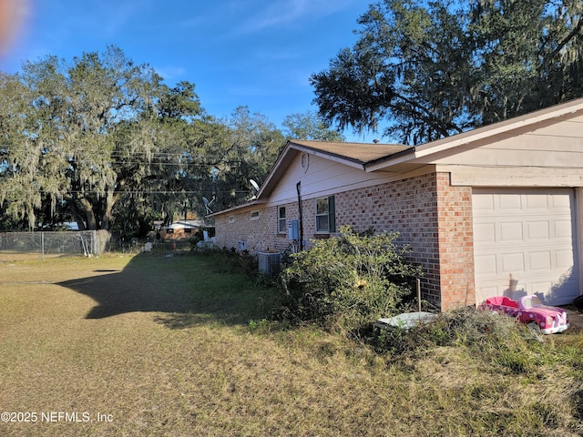 view of side of home featuring central air condition unit, a yard, and a garage