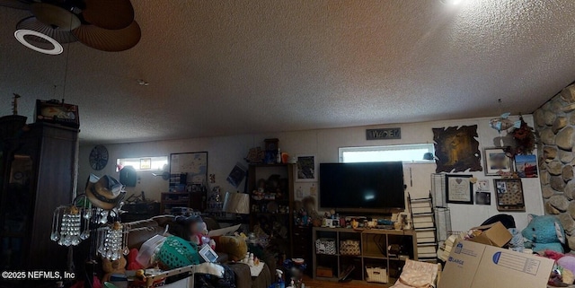 living room featuring ceiling fan and a textured ceiling