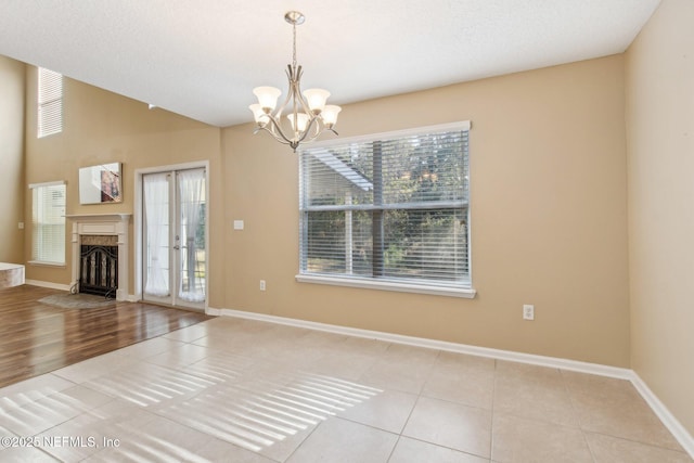 interior space with light tile patterned flooring, french doors, and a chandelier