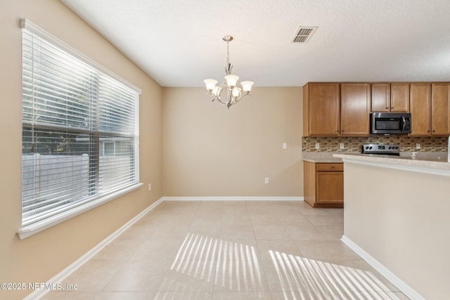 kitchen with decorative backsplash, stove, pendant lighting, a notable chandelier, and light tile patterned flooring