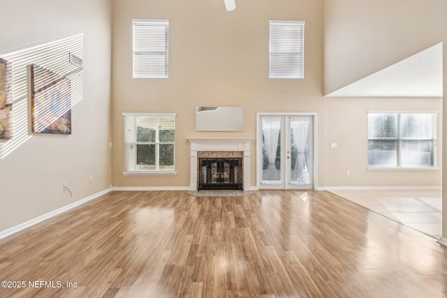 unfurnished living room featuring a premium fireplace, light hardwood / wood-style flooring, and a high ceiling