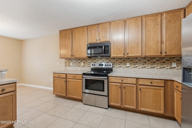 kitchen featuring decorative backsplash, appliances with stainless steel finishes, a textured ceiling, and light tile patterned floors