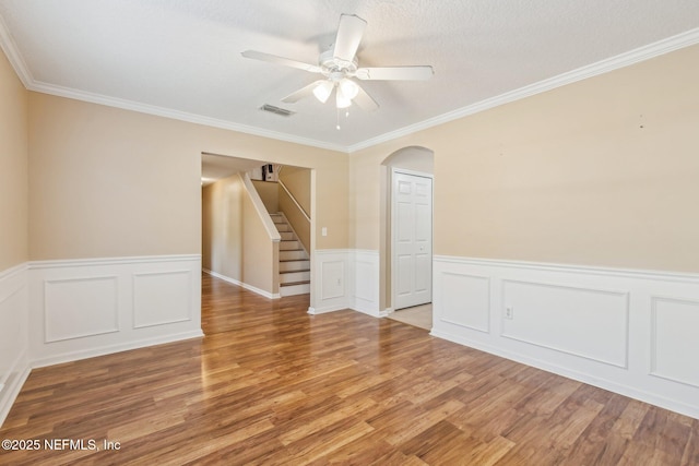 unfurnished room featuring wood-type flooring, a textured ceiling, ceiling fan, and ornamental molding