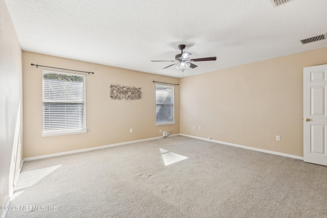 spare room featuring ceiling fan, light colored carpet, and a textured ceiling