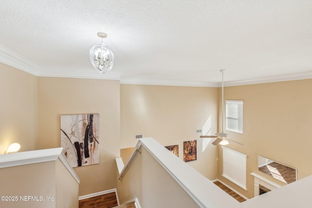 staircase with hardwood / wood-style floors, crown molding, a textured ceiling, and a chandelier