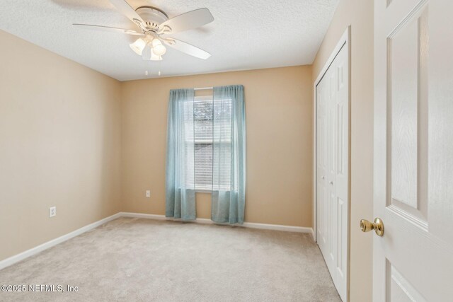 unfurnished bedroom with ceiling fan, a closet, and light carpet