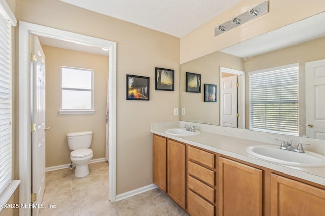 bathroom featuring a textured ceiling, vanity, toilet, and a wealth of natural light