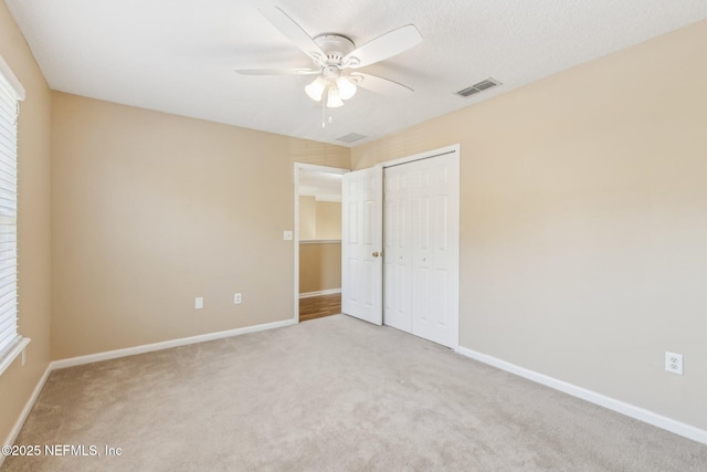 unfurnished bedroom with ceiling fan, light colored carpet, and a closet