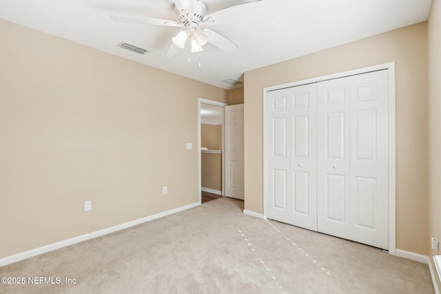 unfurnished bedroom with ceiling fan, light carpet, and a closet