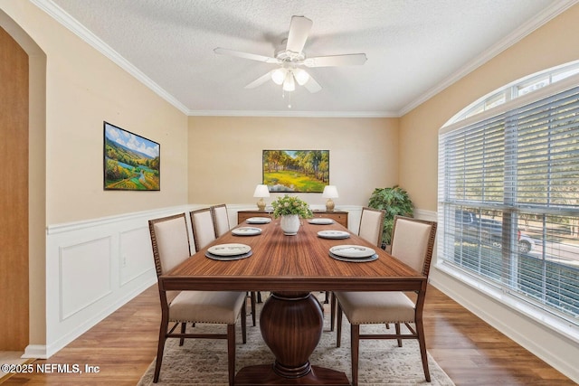 dining area featuring ceiling fan, hardwood / wood-style floors, crown molding, and a textured ceiling