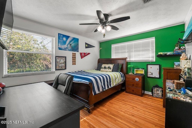 bedroom featuring a textured ceiling, light hardwood / wood-style floors, ceiling fan, and ornamental molding