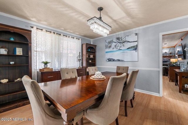 dining space featuring crown molding, light hardwood / wood-style floors, and an inviting chandelier