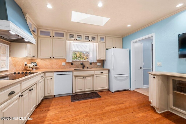 kitchen with white cabinets, white appliances, a skylight, and custom exhaust hood