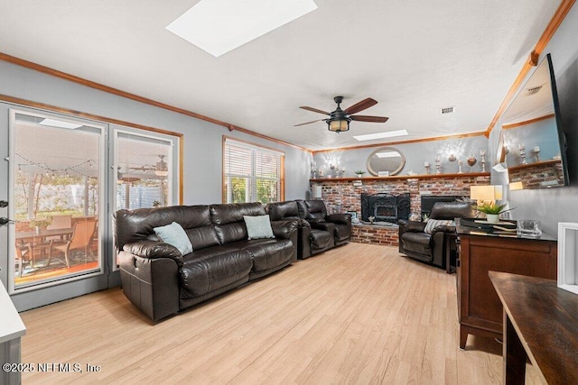 living room with a skylight, ceiling fan, crown molding, light hardwood / wood-style floors, and a wood stove