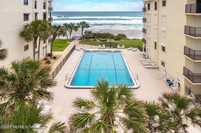 view of swimming pool featuring a water view and a beach view