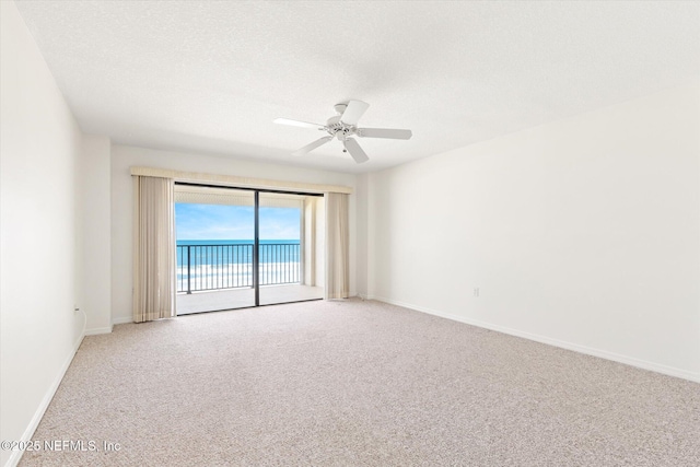 spare room featuring a textured ceiling, carpet floors, a water view, and ceiling fan