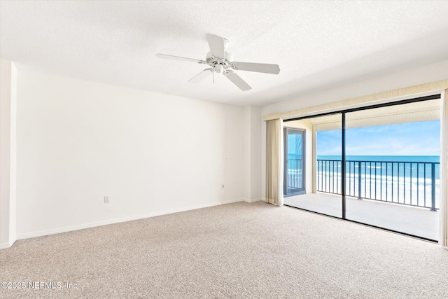 spare room featuring carpet flooring, ceiling fan, a water view, and a textured ceiling